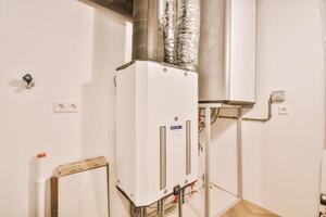 A white water heater in a room with a wall photo