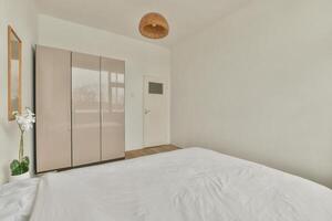 A bedroom with a bed, a wardrobe and a window photo
