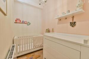 A baby's room with a crib, a dresser and a wall with a shelf photo