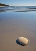 Isolated Rock on a Smooth Beach at Low Tide photo