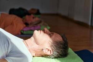 Senior woman practicing stretching and meditation on the floor, focusing on proper alignment and relaxation. photo