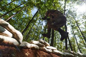 An elite soldier adeptly clears military barriers in the perilous wooded terrain, showcasing tactical skill and agility during specialized training photo