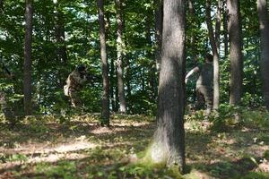 An elite soldier, camouflaged and stealthily navigating through dangerous woodland terrain, executes a covert mission in a secluded forest area photo