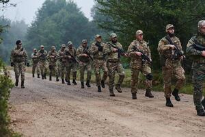 An elite military unit, led by a major, confidently parades through dense forest, showcasing precision, discipline, and readiness for high-risk operations photo