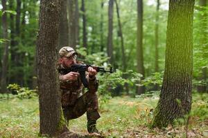 An elite soldier, camouflaged and stealthily navigating through dangerous woodland terrain, executes a covert mission in a secluded forest area photo