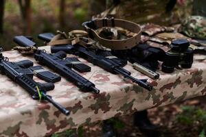 An array of military weapons, including rifles and pistols, is meticulously arranged on a table in a military base, presenting a close-up view of the diverse firepower and armament meticulously photo