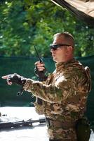 A military major employs a Motorola radio for seamless communication with his fellow soldiers during a tactical operation, showcasing professionalism and strategic coordination photo