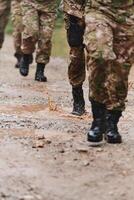 Close up photo, the resilient legs of elite soldiers, clad in camouflage boots, stride purposefully along a hazardous forest path as they embark on a high-stakes military mission photo