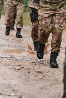 Close up photo, the resilient legs of elite soldiers, clad in camouflage boots, stride purposefully along a hazardous forest path as they embark on a high-stakes military mission photo