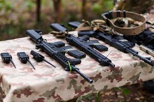 An array of military weapons, including rifles and pistols, is meticulously arranged on a table in a military base, presenting a close-up view of the diverse firepower and armament meticulously photo