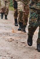 Close up photo, the resilient legs of elite soldiers, clad in camouflage boots, stride purposefully along a hazardous forest path as they embark on a high-stakes military mission photo