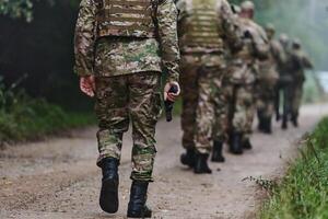 Close up photo, the resilient legs of elite soldiers, clad in camouflage boots, stride purposefully along a hazardous forest path as they embark on a high-stakes military mission photo