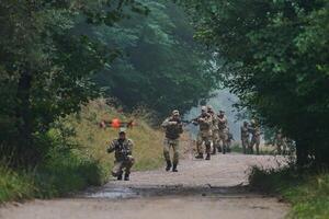 Elite military unit parading and securing the forest, utilizing drones for terrain scanning and reconnaissance, showcasing their advanced skills and specialized training in high risk operations photo