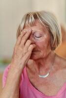 Senior Woman Practicing Calming Traditional Exercises with a Gentle Forehead Gesture photo