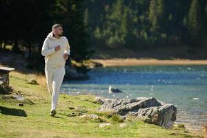 Athletic man maintains his healthy lifestyle by running through the scenic mountain and lakeside environment, showcasing a commitment to fitness and well-being photo