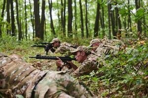 Elite soldiers stealthily maneuver through the dense forest, camouflaged in specialized gear, as they embark on a covert and strategic military mission photo