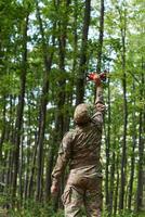 Elite military unit, equipped with state-of-the-art technology including a drone, strategically navigates and surveys dangerous wooded terrain, showcasing their precision, cooperation, and specialized photo