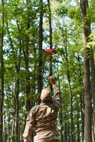 Elite military unit, equipped with state-of-the-art technology including a drone, strategically navigates and surveys dangerous wooded terrain, showcasing their precision, cooperation, and specialized photo
