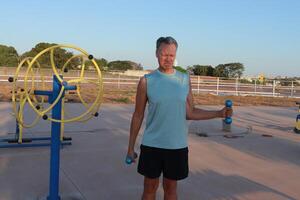 Older Man doing External Shoulder Rotation exercise with light weights for should pain photo