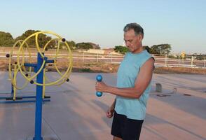 Older Man doing External Shoulder Rotation exercise with light weights for should pain photo