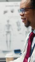 Vertical Doctor and patient discussing diagnostic results in a modern medical office, showcasing advanced healthcare technology using a screen displaying x rays and MRI scans. Care management. Camera A. video