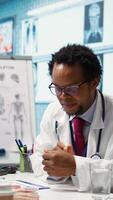 Vertical Medical expert taking oxygen saturation levels with an oximeter, doing measurements and vital signs readings with a digital device with clip. Doctor consulting a patient at appointment. Camera B. video