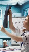 Vertical General practitioner consults patient about diagnostic test results, utilizing medical technology for analysis and patient care management in a clinical environment. Healthcare provider. Camera B. video