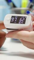 Vertical Medical specialist takes the oxygen saturation measurement and checking vital signs during a routine check up with her patient. Medic using an oximeter for accurate readings in office. Camera A. video