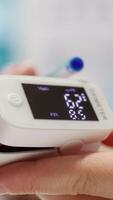 Vertical Medical specialist takes the oxygen saturation measurement and checking vital signs during a routine check up with her patient. Medic using an oximeter for accurate readings in office. Camera B. video