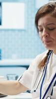 Vertical Medical expert discusses test results with a patient in a healthcare setting, utilizing diagnostic tools and computer technology for accurate medical analysis and consultation. Camera A. video