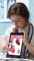 Vertical Healthcare provider cardiologist explains heart function on a cardiogram, doctor patient interaction in a medical office. Medic highlighting the possible condition, cardiovascular system. Camera A. video