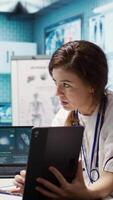 Vertical General practitioner presenting the test findings via scan interpretation on tablet, discussing about the diagnostic and possible treatment. Medical expert provides advice to patient. Camera B. video