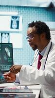 Vertical Medical expert specialist explaining the x ray imaging for a diagnosis, doing scan interpretation during check up consultation. Professional medic gives feedback to female client. Camera B. video
