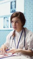 Vertical Healthcare professional sharing her medical expertise with a patient in a cabinet, reviewing x ray and MRI scans and focusing on accurate diagnostics and patient care. Diagnostic report. Camera B. video