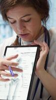 Vertical Healthcare provider presenting lab test results to a patient in cabinet, reviewing x ray and MRI scans to assist man through recovery. Medical technology in diagnostics and care management. Camera A. video