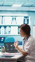 Vertical Female doctor and patient engage in a medical consultation with diagnostic tools and x ray imaging visible on the screen. Emphasizing modern healthcare practices and medical research. Camera B. video
