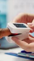 Vertical Doctor with expertise uses an oximeter to measure the oxygen saturation for a patient during examination, diagnostic tools for support. Consulting man with professional oximetry readings. Camera B. video