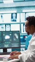 Vertical Doctor reading x ray imaging for a diagnostic report at consultation, discussing with a patient about medicine. Physician examining lab test results and analysis, health insurance. Camera B. video