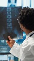 Vertical Physician reviewing MRI scan and x ray results with a patient in medical office, explaining the diagnostics. Doctor pointing at analysis to discuss about the illness, medical technology. Camera A. video
