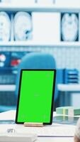 Vertical General practitioner pointing at green screen mockup on device, discussing with her patient about recovery treatment. Doctor doing checkup visit on insurance with a man. Camera A video