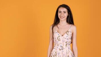 Happy woman in summer dress showing thimbs up isoalted on orange yellow background in studio video