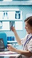 Vertical Medical staff reviewing diagnostic reports and results for a patient, focusing on x ray imaging and scan interpretation. Modern medical examination and patient diagnosis at clinic. Camera B. video