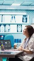 Vertical Physician meets with a patient to discuss medical results in a cabinet, using advanced diagnostic equipment to interpret x ray scans, demonstrating a professional healthcare approach. Camera B. video