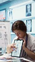 Vertical Healthcare provider presenting lab test results to a patient in cabinet, reviewing x ray and MRI scans to assist man through recovery. Medical technology in diagnostics and care management. Camera B. video