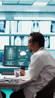 Vertical General practitioner presenting the diagnostic report at checkup with patient, discussing about treatment plan. Medic showing x ray imaging and scans on computer, medical results. Camera B. video