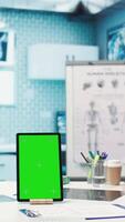 Vertical General practitioner pointing at green screen mockup on device, discussing with her patient about recovery treatment. Doctor doing checkup visit on insurance with a man. Camera B. video