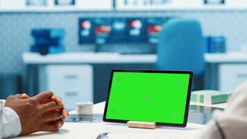 Physician specialist looking at chroma key display in medical office, doing a consultation with a diagnostic report. Medic consulting african american patient during checkup. Camera A. video