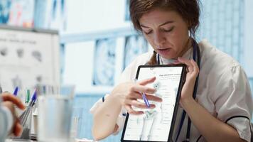 Healthcare provider presenting lab test results to a patient in cabinet, reviewing x ray and MRI scans to assist man through recovery. Medical technology in diagnostics and care management. Camera A. video