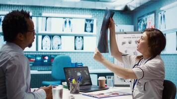 General practitioner consults patient about diagnostic test results, utilizing medical technology for analysis and patient care management in a clinical environment. Healthcare provider. Camera B. video
