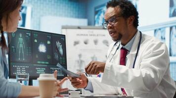Medical expert specialist explaining the x ray imaging for a diagnosis, doing scan interpretation during check up consultation. Professional medic gives feedback to female client. Camera A. video